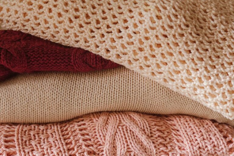 Folded cashmere and wool sweaters stacked side by side showing texture difference