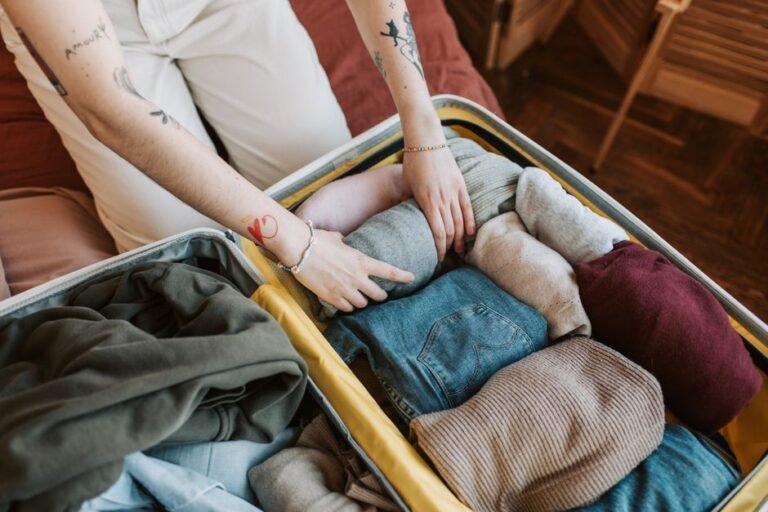 Folded sweaters and clothing being packed into a storage bin