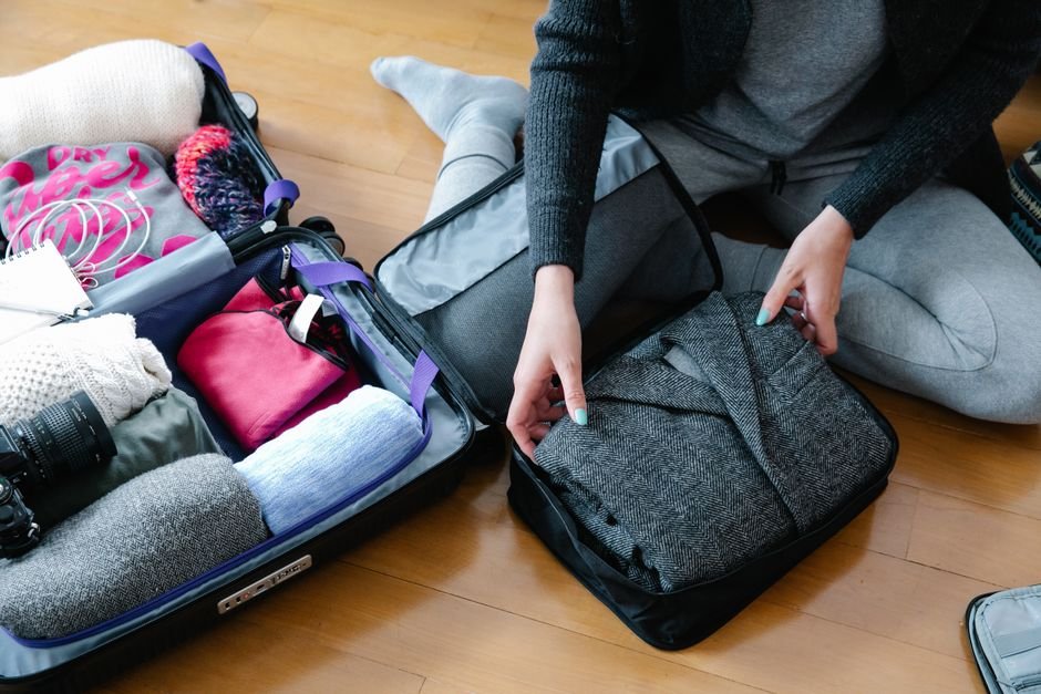 Five folded clothing items laid out on a bed
