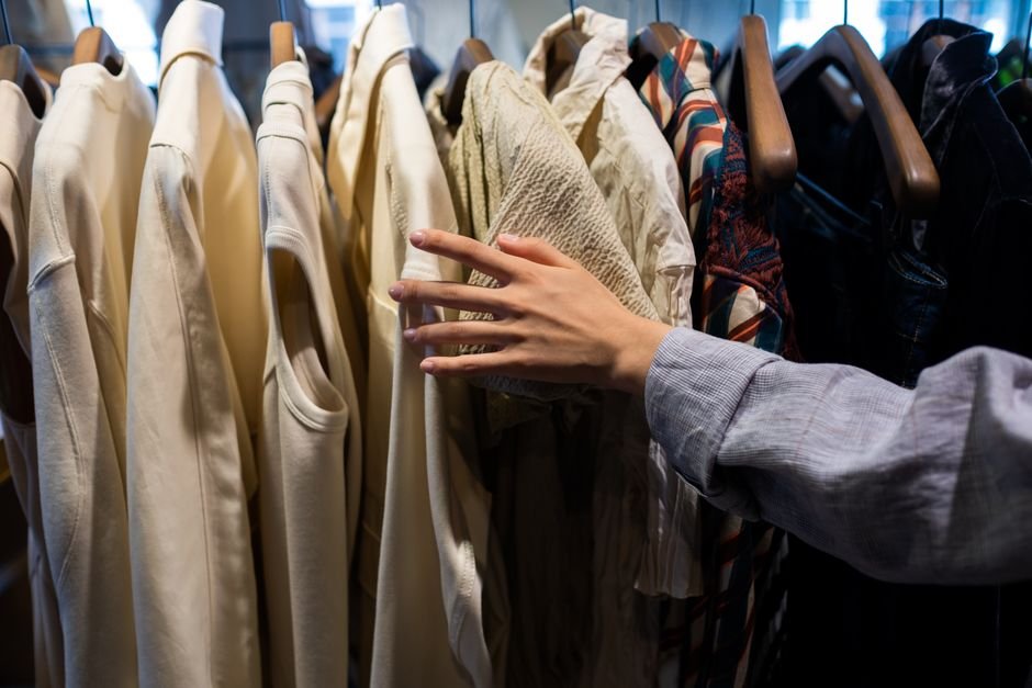 A hand feeling the texture of a fabric swatch on a clothing rack in a store