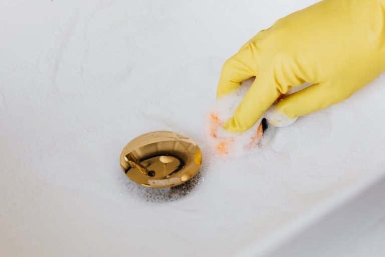 A person using a plastic zip tool to clear hair from a bathroom sink drain