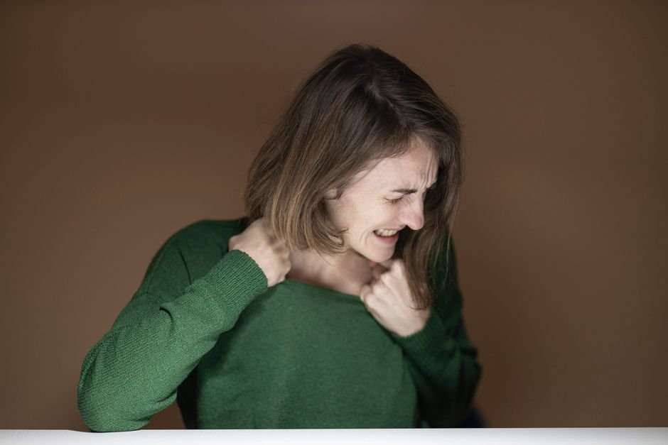 A person pulling a sweater over their head with static causing their hair to stand up