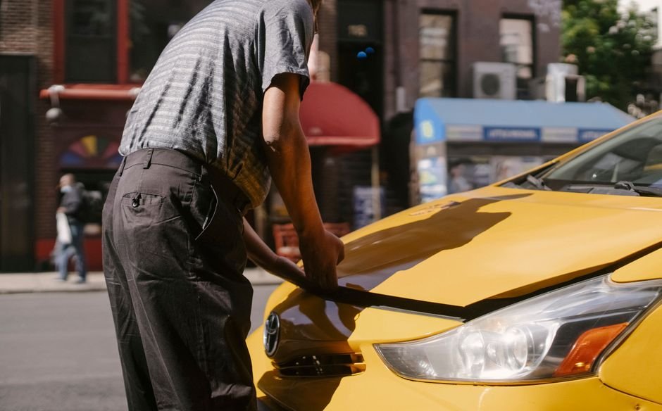A person photographing the side of a rental car in a parking lot