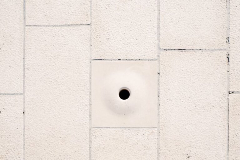 A person using a putty knife to smooth joint compound over a small patched hole in a wall