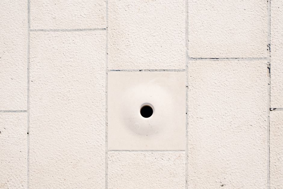 A person using a putty knife to smooth joint compound over a small patched hole in a wall
