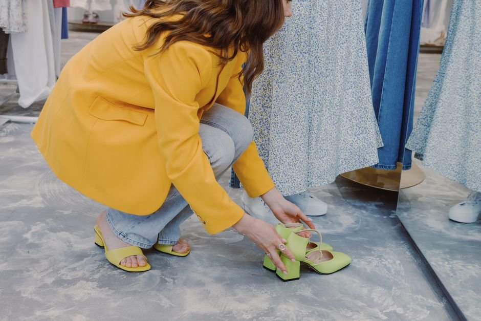 A person trying on shoes and checking the fit while standing in a shoe store