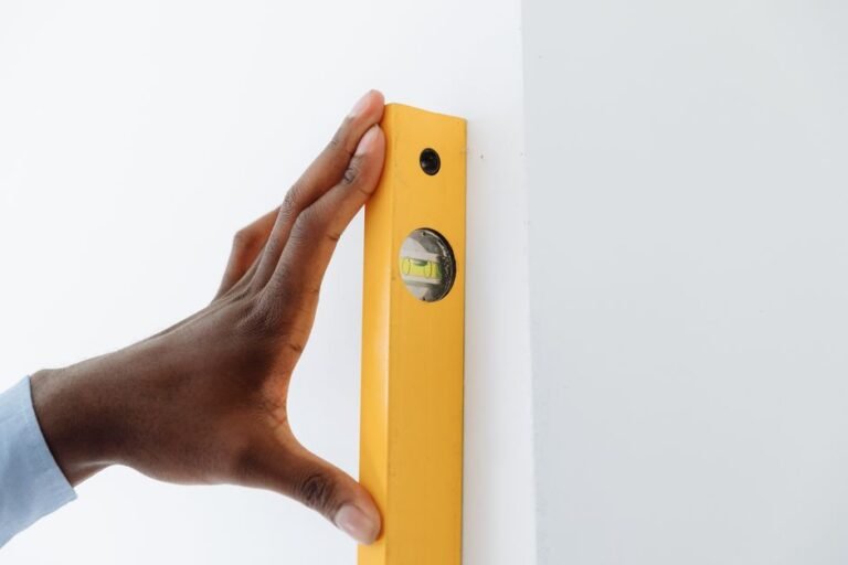 A person holding a stud finder against a wall while marking a spot with a pencil