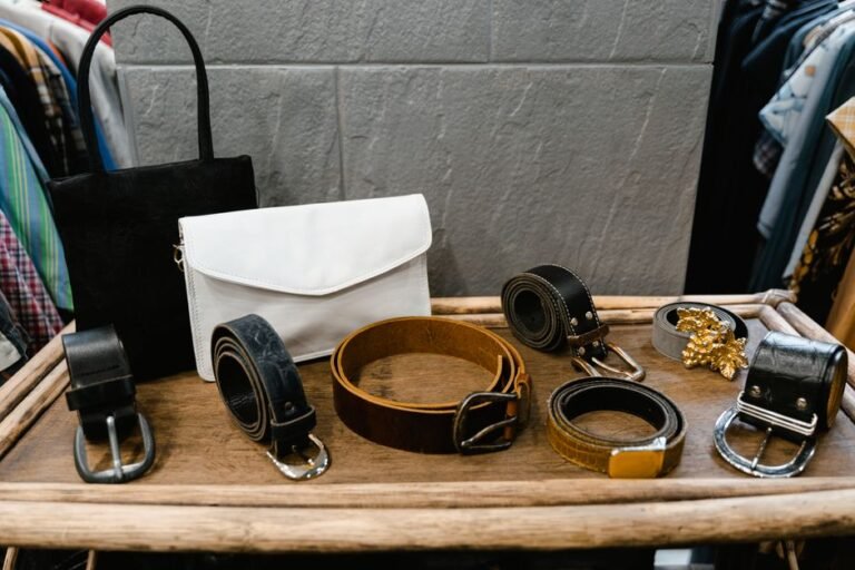 Several leather belts of varying widths laid out side by side on a wooden table
