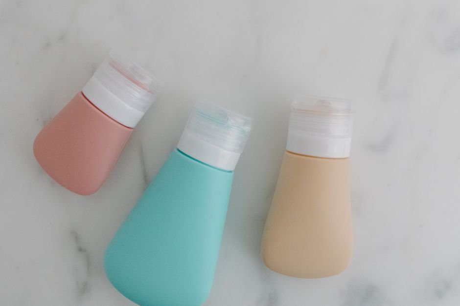 A clear zippered toiletry bag holding small travel-size bottles and tubes