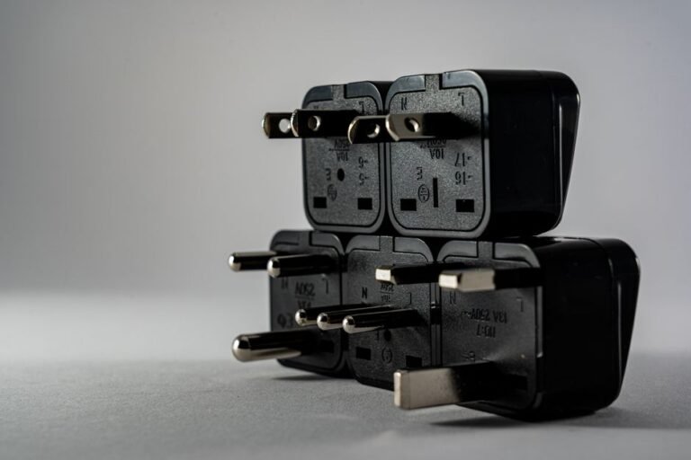 A universal travel adapter with folding prongs plugged into a wall outlet