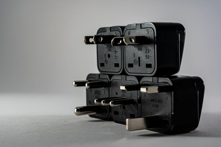 A universal travel adapter with folding prongs plugged into a wall outlet