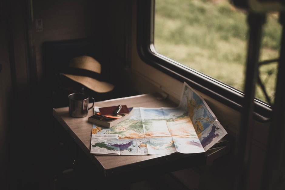A printed travel itinerary lying on top of a folded paper map