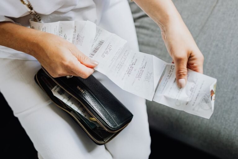A traveler at a café table sorting paper receipts next to an open budget notebook